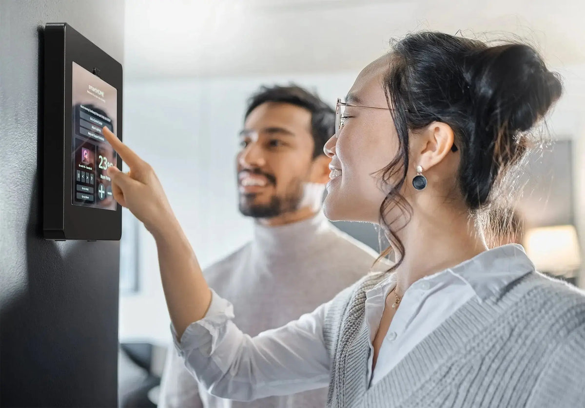 Two colleagues using an iPad in a black locking enclosure mounted on an office wall