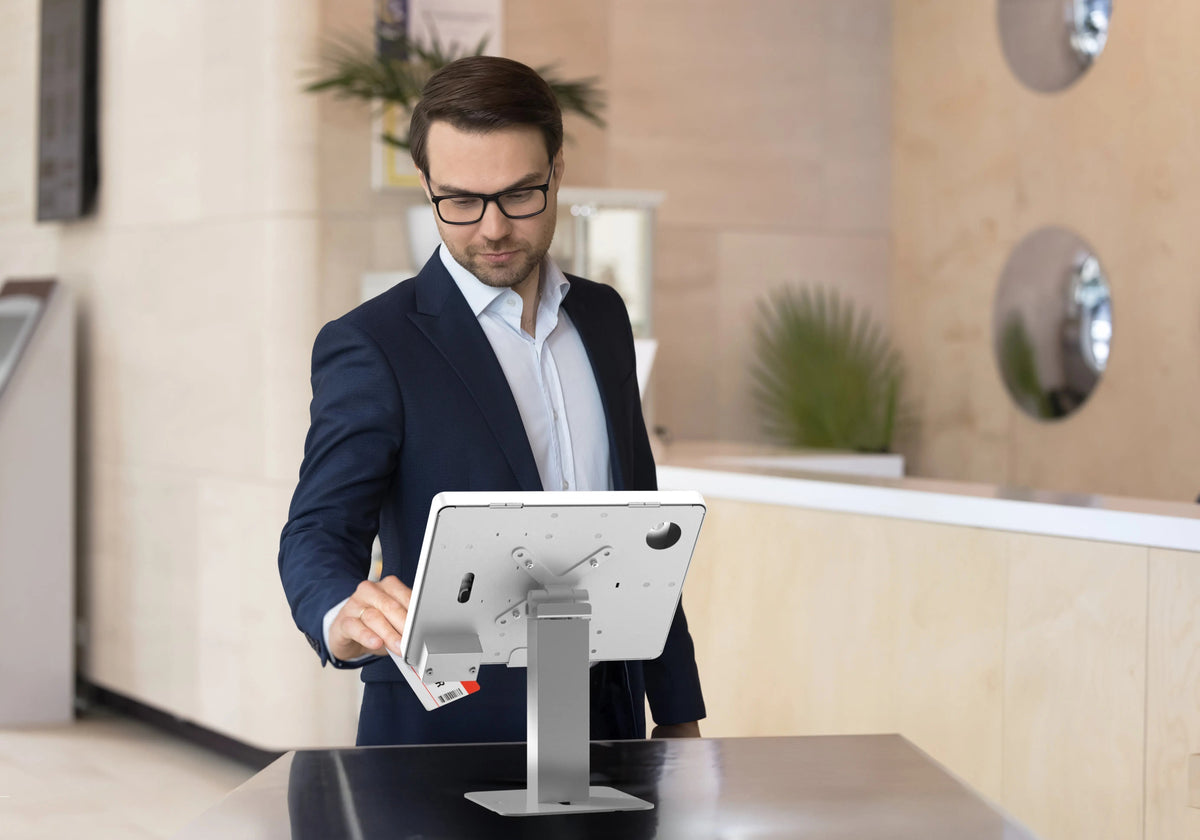 Staff member using a tablet on a stand at a reception counter