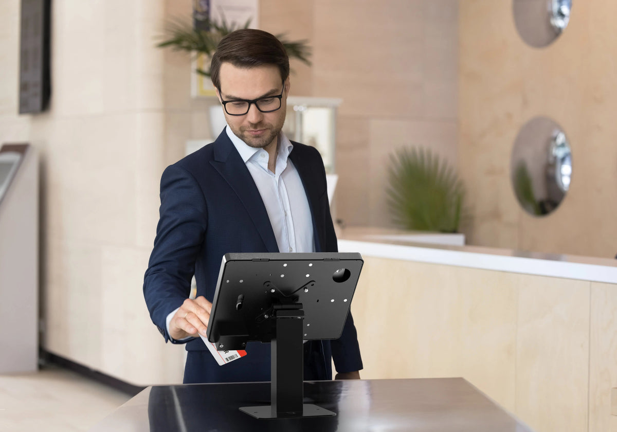 Visitor using a tablet on a locking stand at a reception counter