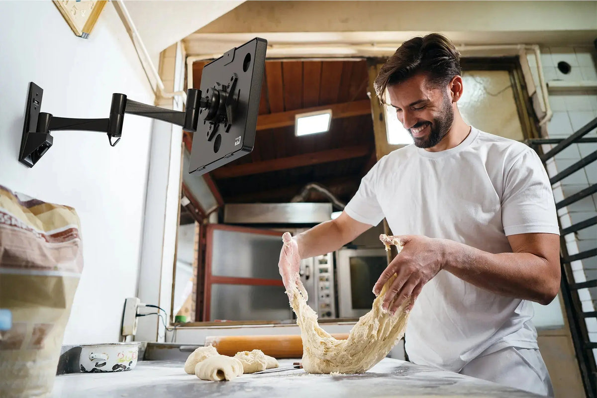 Baker kneading dough under a tablet held on an articulating VESA wall arm