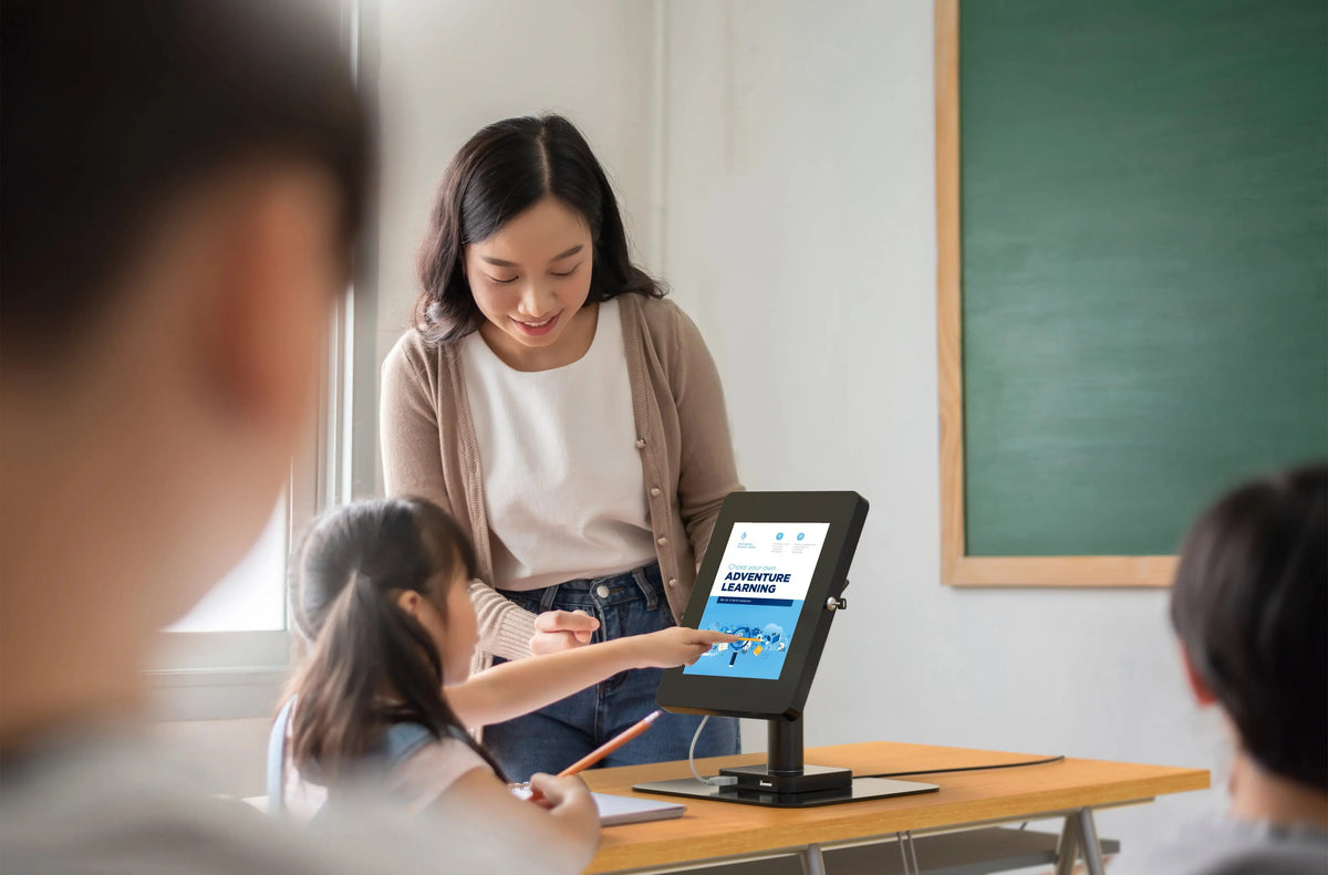 Teacher and student using a tablet on a desk stand in a classroom